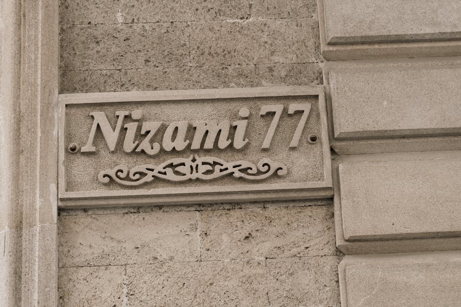 Street sign labeled 'Nizami 77' on stone facade in Baku, Azerbaijan.