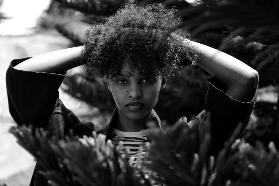 A striking black and white portrait of a woman amid foliage in Kigali, Rwanda.