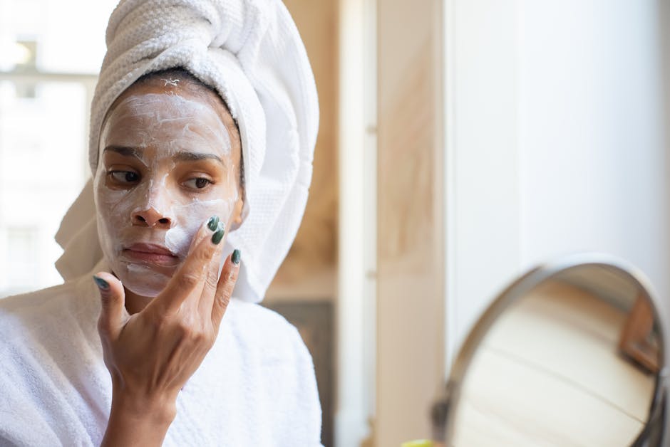 Woman applying cream on her face during morning skincare routine in the bathroom.