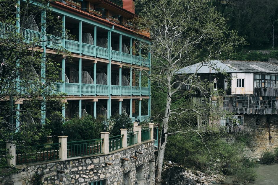 An abandoned building with vibrant railings in a rural setting surrounded by nature.