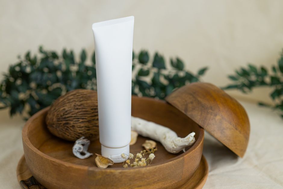Close-up of a skincare cream tube in a wooden bowl with natural elements.