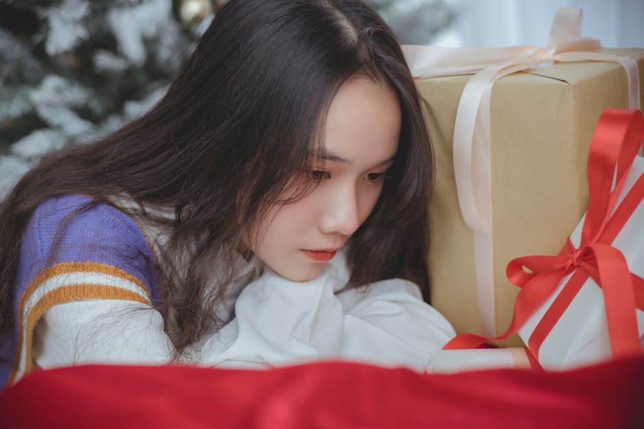 Pensive young woman sitting beside beautifully wrapped Christmas gifts indoors.