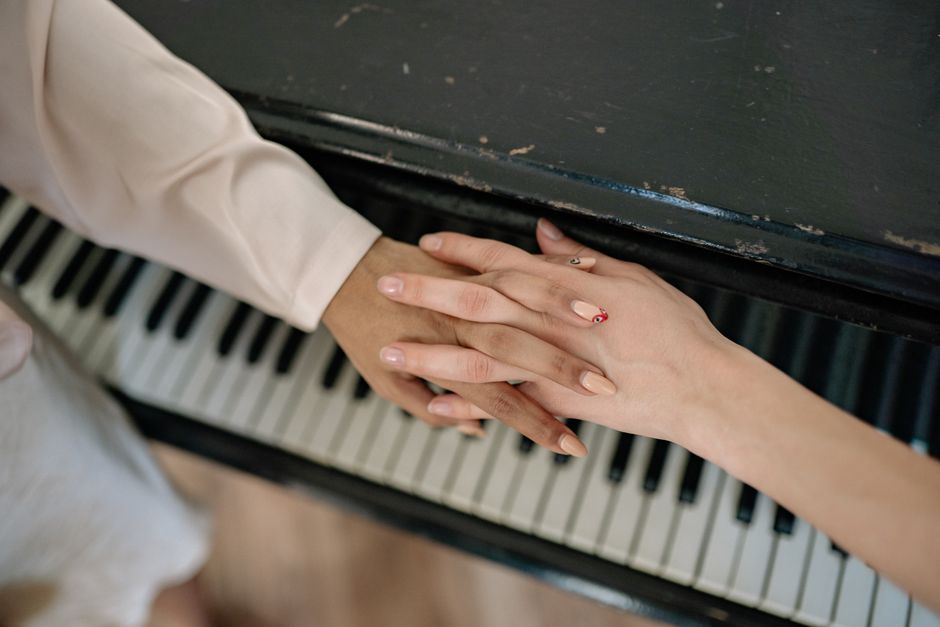 Close-up of two hands resting gently on piano keys, highlighting intimacy and music connection.