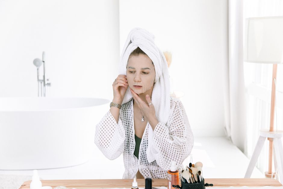 A woman applies a face mask as part of her skincare routine in a modern bathroom.
