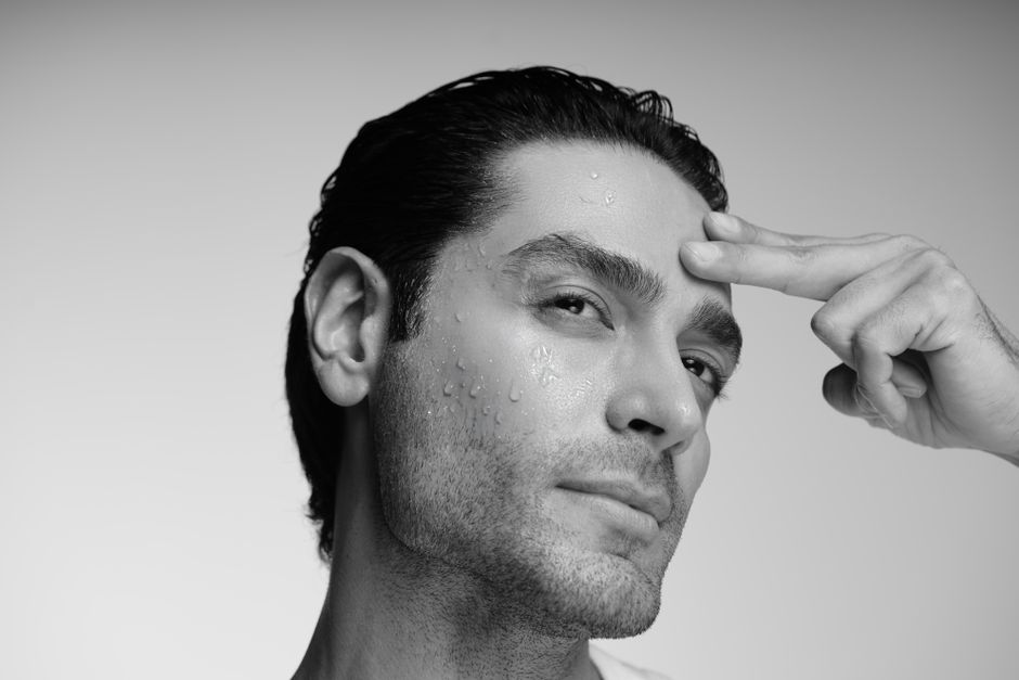 A close-up black and white portrait of a man with wet skin, offering a dramatic and emotive look.