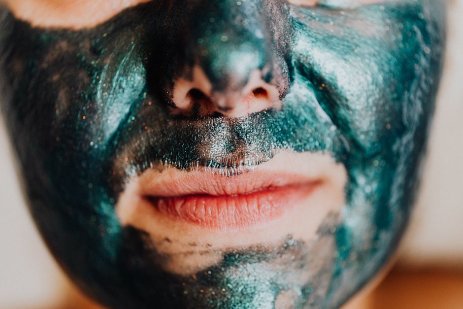 Intimate close-up of a person wearing a shimmering green facial mask promoting skincare.