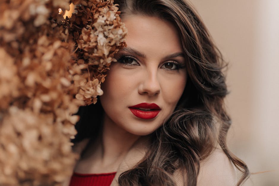 Charming close-up of an elegant brunette woman with red lipstick surrounded by dried flowers.