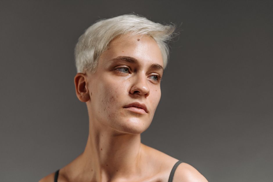Close-up portrait of a woman with short white hair looking away thoughtfully.
