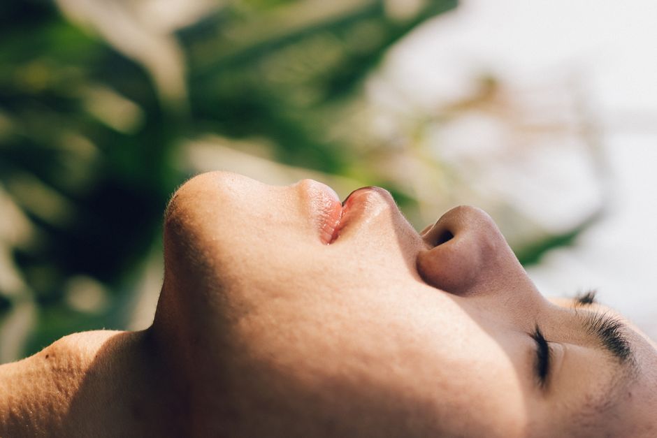 Close-up side view of a relaxed man with eyes closed outdoors.
