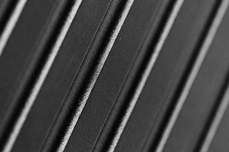 Abstract macro shot of a black textured surface showcasing intricate diagonal lines.