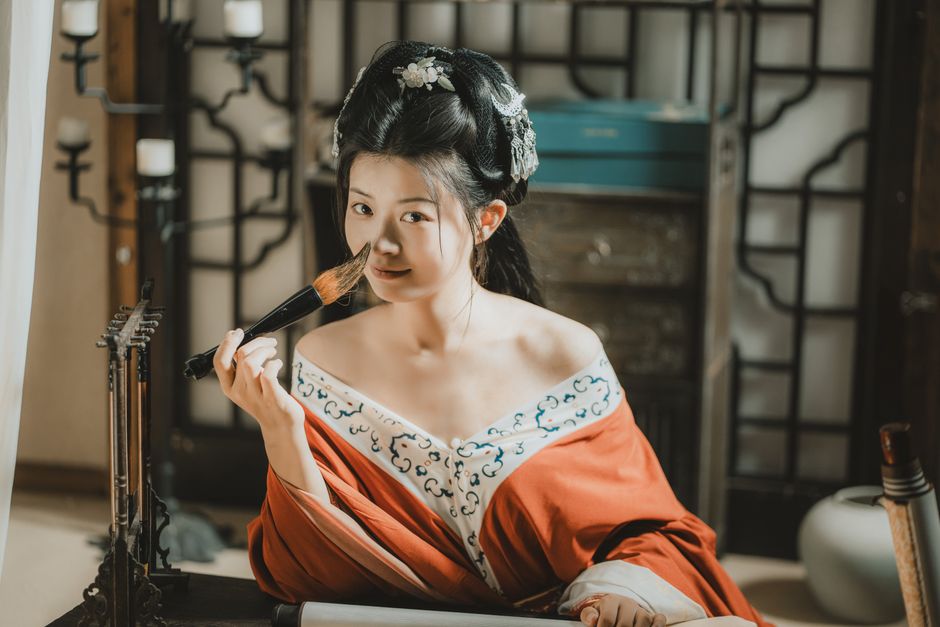A woman in traditional Asian attire with intricate hairstyle posing indoors.