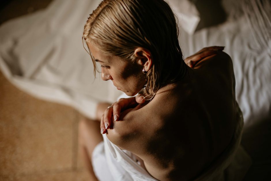 A woman with wet hair wrapped in a towel, captured in a serene, intimate indoor setting.