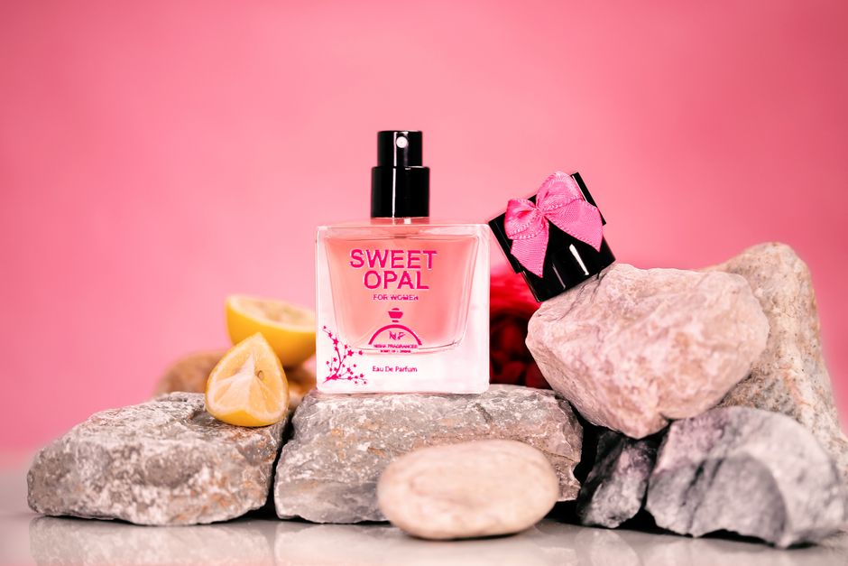 Chic perfume bottle arranged with rocks and lemon slices on a pink backdrop.