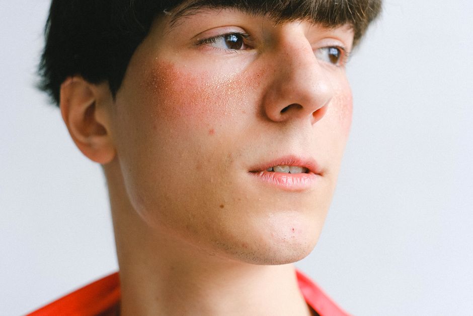 A close-up portrait of a young caucasian man looking thoughtfully to the side, with natural lighting highlighting his features.