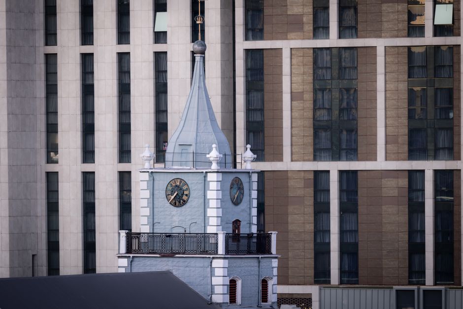 A historic clock tower stands contrastingly against a modern skyscraper facade.
