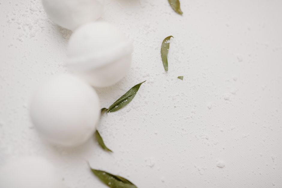 Elegant bath bombs with green leaves against a minimalist background, ideal for self-care themes.