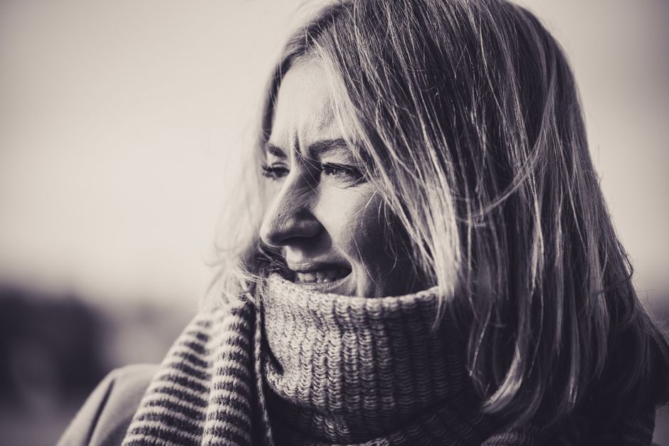 Black and white portrait of a woman wearing a cozy knitted scarf, enjoying the outdoors.